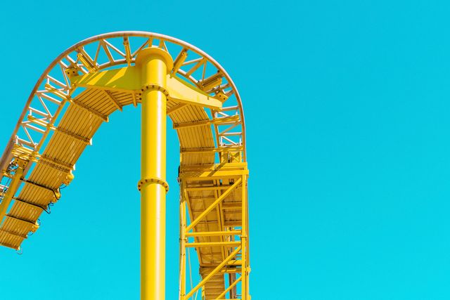 Bright yellow roller coaster stands out against clear blue sky, suggesting excitement and adventure. Ideal for promoting amusement parks, thrill rides, summer activities, or colorful architectur recommendations. Versatile for digital marketing, calendars, travel blogs, and brochures.