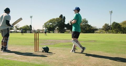 Diverse cricketers defending wicket and appealing run out on sunny community pitch