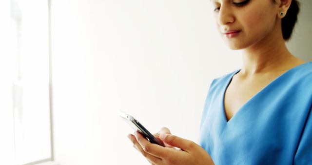 Young Woman in Blue Dress Using Smartphone by Window - Download Free Stock Images Pikwizard.com