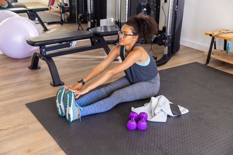 Fitness enthusiast stretching on gym mat with weights