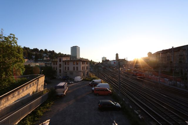 Urban scene with sunset, railway yards, and buildings in background. Great for urban landscape themes, transportation industry focuses, and city development projects.