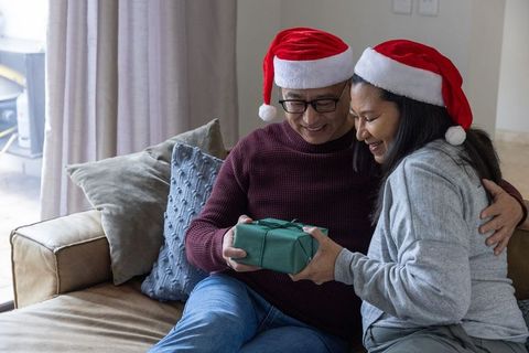 Elderly Couple Sharing Christmas Gift Happy on Sofa in Holiday Spirit
