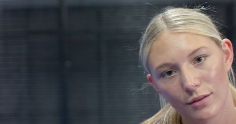Focused Female Athlete in Gym with Mesh Fencing Backdrop