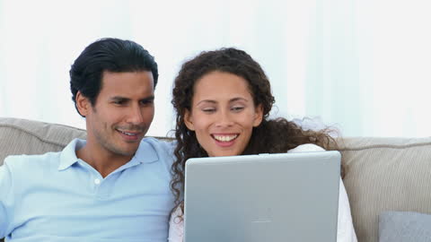 Happy Couple Relaxing and Watching Video on Laptop at Home