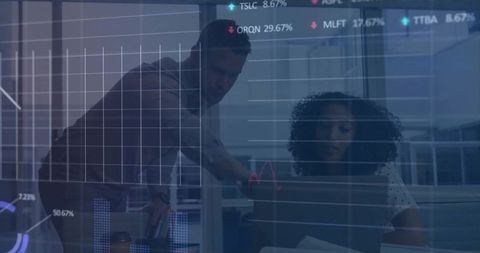 Colleagues analyzing interactive dashboards on laptop while collaborating in modern office