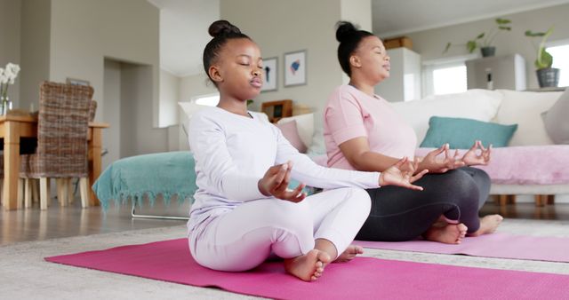 Black mother and daughter meditating together in a living room - Download Free Stock Images Pikwizard.com