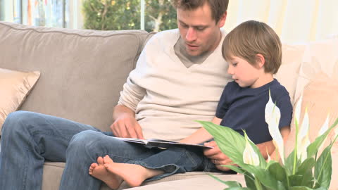 Father Reading Storybook to Son on Cozy Sofa