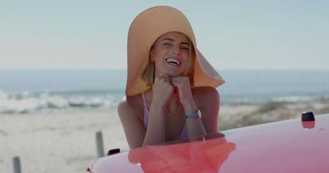 Woman Enjoying Beach Day by Red Convertible with Straw Hat