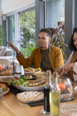 African american friends sharing casual sunlit dinner conversation at modern dining table