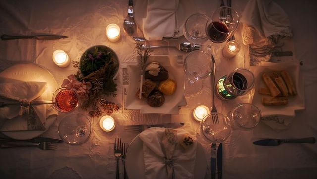 Glowing candlelit dinner table with votive candles, wine glasses and dessert pastries