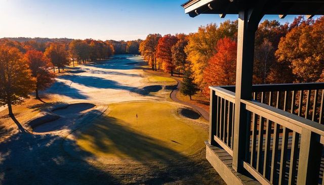 Elevated autumn golf course overlooking frosty putting green, bunkers and sunrise light