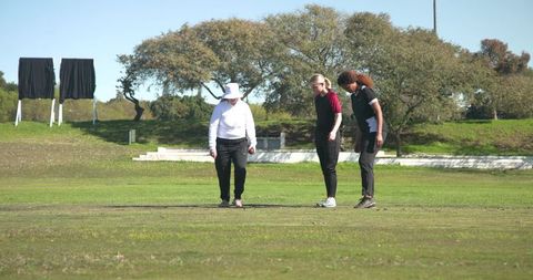 Women Golfers Analyzing Turf on Sunny Golf Course