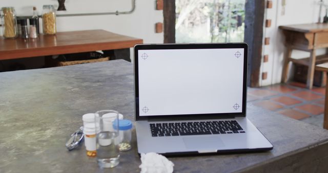 Modern Kitchen Island Workspace with Open Laptop and Medication Bottles - Download Free Stock Images Pikwizard.com