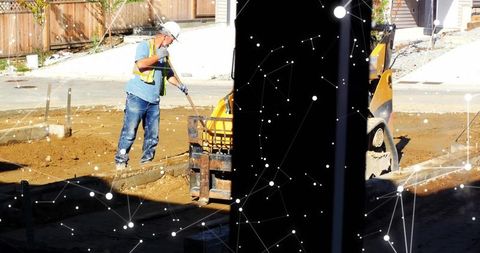 Construction worker spreading soil at building site