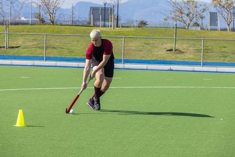 Male athlete dribbling hockey ball on field during training
