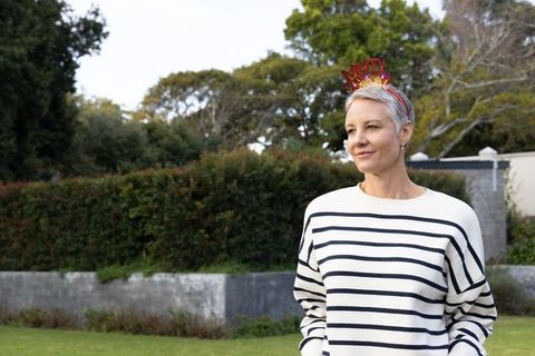 Serene mature woman wearing merry headband standing in garden with striped pullover