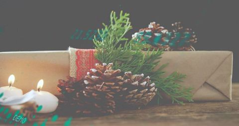 Rustic gift wrapping evoking cozy holiday mood with pinecones, evergreen sprigs and candlelight