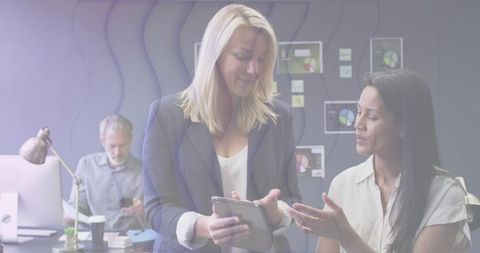 Two Business Women Collaborating on Tablet in Modern Office