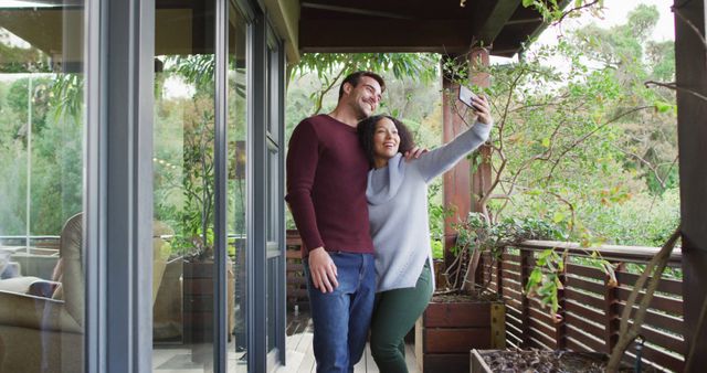 Biracial couple smiling while taking a selfie on smartphone in the balcony at vacation home - Download Free Stock Photos Pikwizard.com