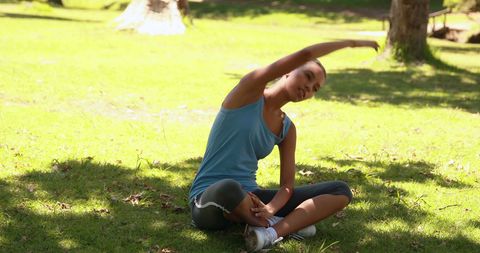 Woman Exercising with a Side Stretch in Sunny Park
