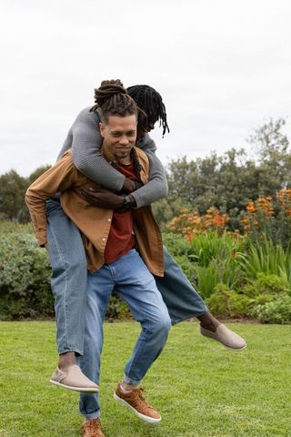 African american friends playing piggyback in garden laughing and bonding