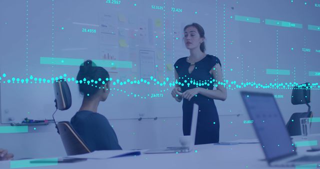 Businesswoman standing and presenting data analysis during a meeting with colleagues in an office. Overlays of digital data and graphs emphasize the use of technology in the business discussion. Useful for illustrating corporate strategy sessions, teamwork and collaborative decision-making, technology in business, and professional presentations.