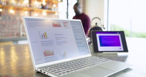 Mid adult African American man working at cafe with laptop showing analytics dashboard