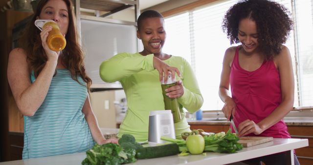 Diverse happy female friends trying healthy drinks at home. female friends hanging out enjoying leisure time together.