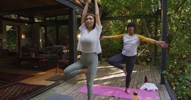 Asian mother and daughter practicing yoga outdoors in garden. at home in isolation during quarantine lockdown.