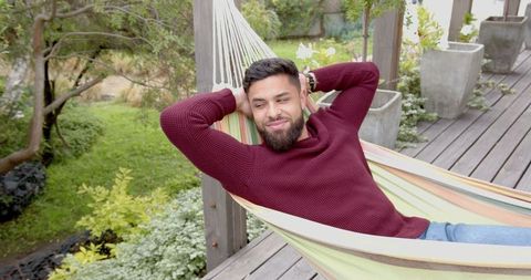 Young man relaxing in hammock on serene outdoor deck