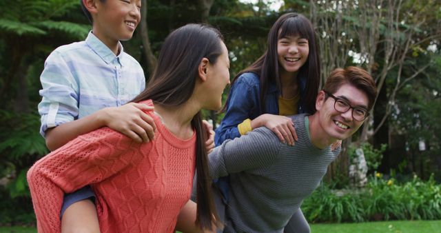 Cheerful family enjoying playful piggyback ride outdoors in garden - Download Free Stock Images Pikwizard.com