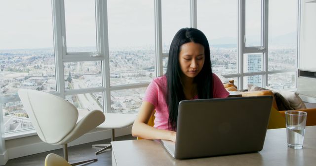 Focused Woman Working on Laptop in Modern High-Rise Apartment - Download Free Stock Images Pikwizard.com