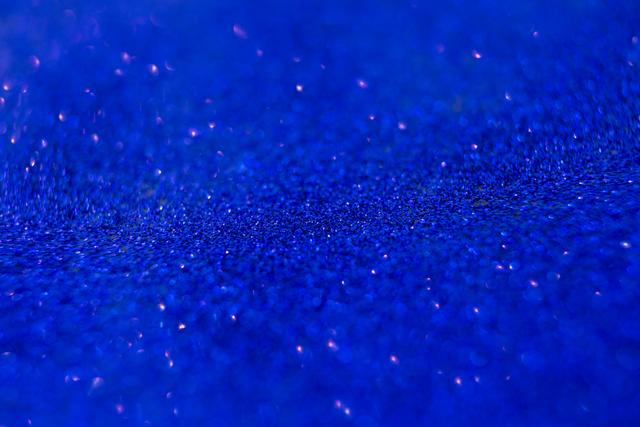 This image captures a close-up view of blue glitter, creating a sparkling and vibrant texture. Ideal for use in holiday and Christmas-themed designs, festive decorations, and as a background for celebratory events. Perfect for adding a touch of sparkle to invitations, greeting cards, and digital graphics.