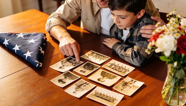 Man and boy remembering military family history while reviewing vintage service photos