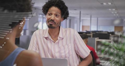 Engaging male colleague leaning forward in collaborative open-plan office conversation