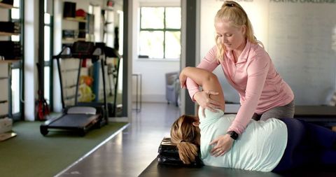 Physical Therapist Guiding Female Patient in Rehabilitation Exercise