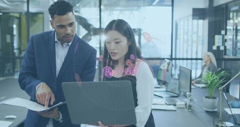 Business team collaborating over laptop with floating data visualization in open office