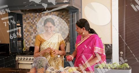 Indian Mother and Daughter Preparing Fresh Produce at Kitchen Island in Sarees