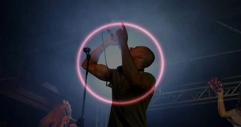 Singing vocalist under neon pink halo ring during high energy live concert performance