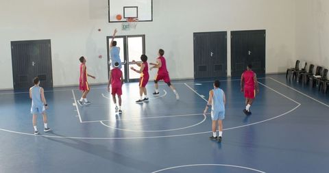 Diverse male basketball teams competing in indoor court