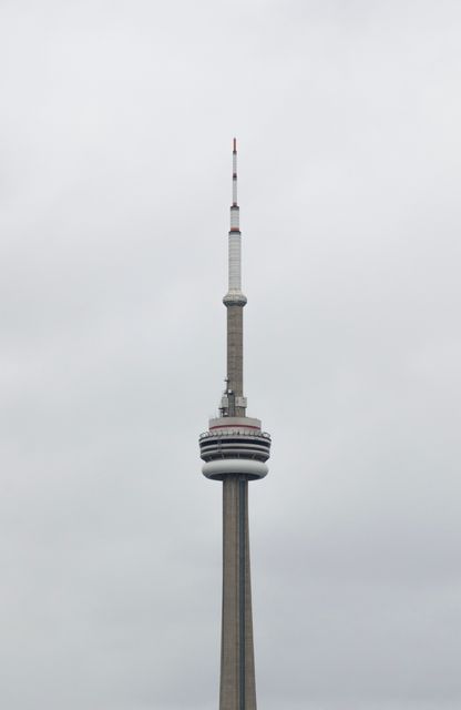 CN Tower standing tall against a cloudy sky. Perfect for travel guides, promoting tourism, Canadian landmarks, and architecture presentations.