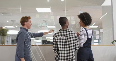 Coworkers Analyzing Ideas on Glass Panel with Sticky Notes