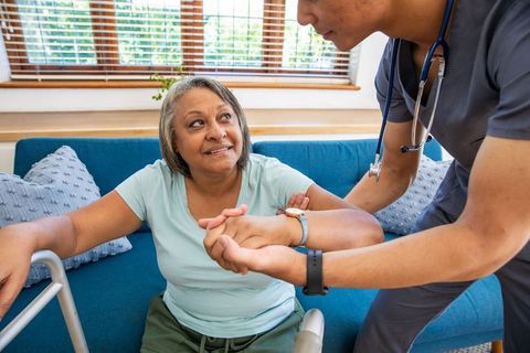 Caregiver Supporting Senior Woman with Walker at Home