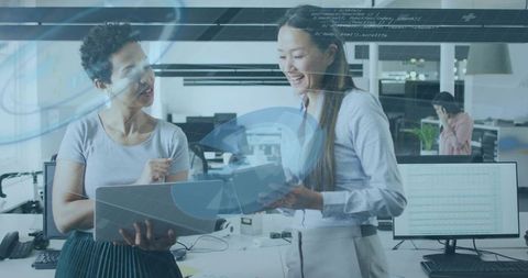 Collaborating women reviewing documents with overlapping data graphics in office