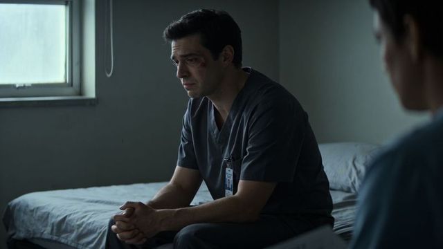 Somber clinician sitting on hospital bed clasping hands with visible bruise