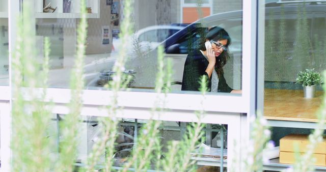 Businesswoman on Phone in Modern Office with Greenery Outside - Download Free Stock Images Pikwizard.com