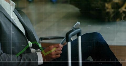 Business traveler using tablet in airport lounge with carry-on and data overlay