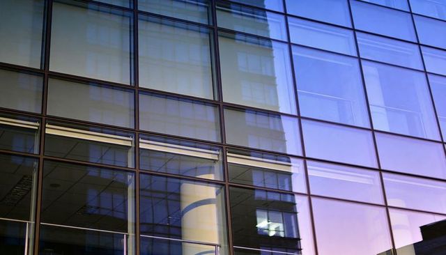 Sunset reflections on glass facade revealing interior column through mullion grid