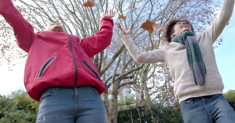 Mother and Son Playing with Autumn Leaves in Warm Clothing