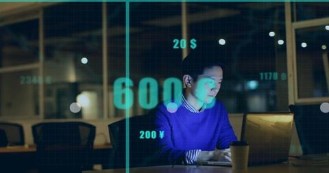 Asian Businessman Typing on Laptop with Financial Data Overlay in Night Office Workspace